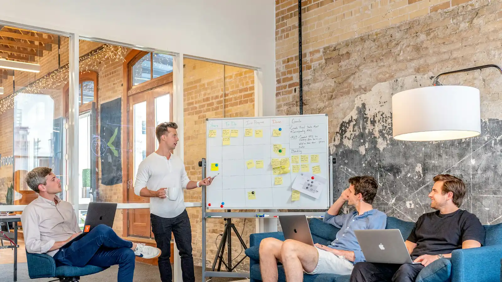 digital marketing mistakes — three men sitting while using laptops and watching man beside whiteboard